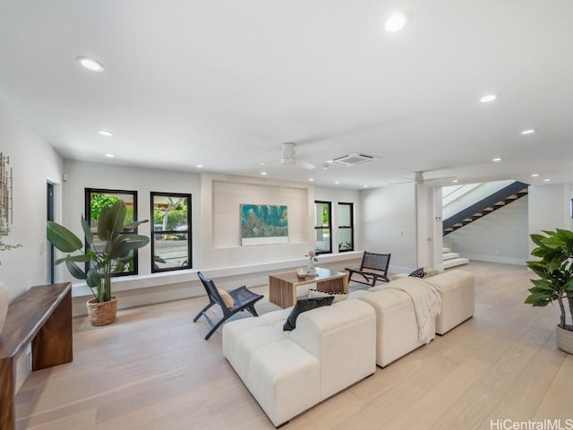 living room with ceiling fan, plenty of natural light, and light wood-type flooring