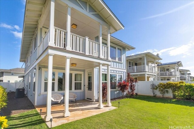 rear view of property with a yard, a balcony, and central AC unit