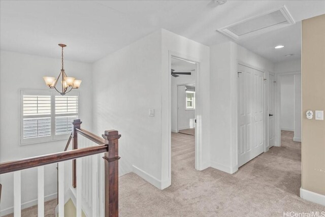 hallway featuring light carpet and an inviting chandelier