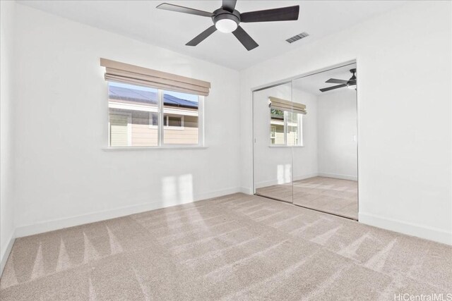 unfurnished bedroom featuring ceiling fan, light colored carpet, and a closet