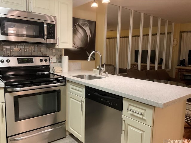 kitchen featuring kitchen peninsula, appliances with stainless steel finishes, backsplash, light stone countertops, and sink