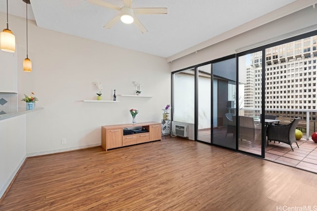 interior space with hardwood / wood-style floors, a wall unit AC, and ceiling fan