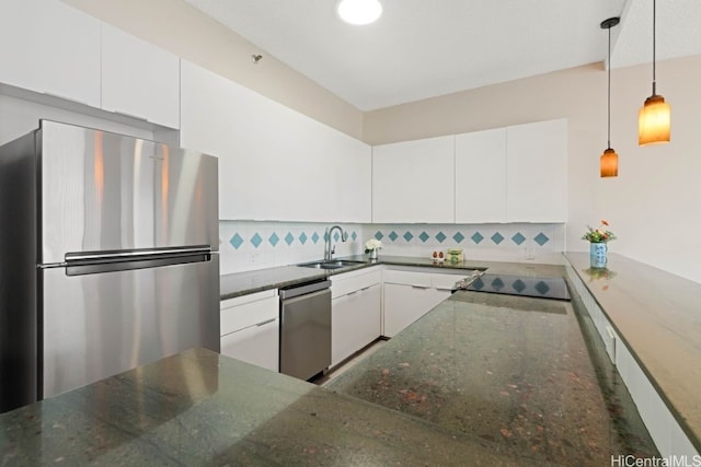 kitchen with dark stone counters, hanging light fixtures, appliances with stainless steel finishes, tasteful backsplash, and white cabinetry