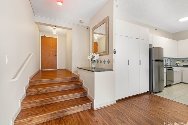 staircase featuring hardwood / wood-style floors, sink, and a textured ceiling