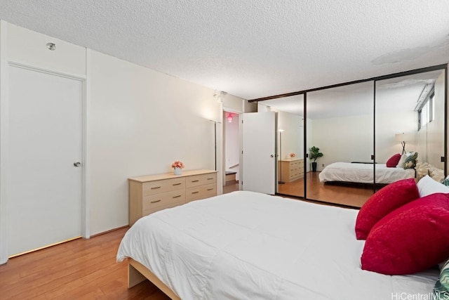 bedroom with a closet, a textured ceiling, and light wood-type flooring