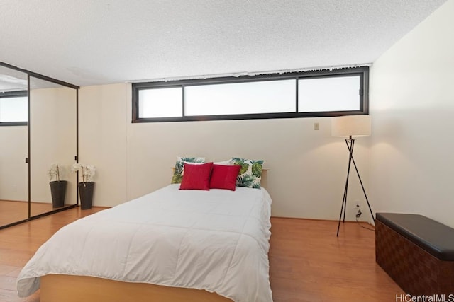 bedroom featuring light hardwood / wood-style floors and a textured ceiling