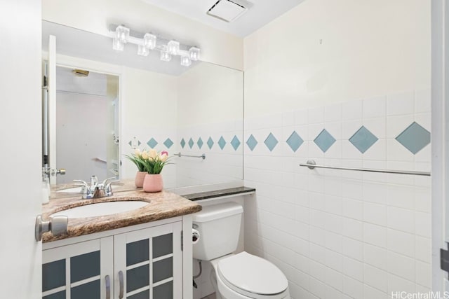 bathroom with vanity, toilet, and tile walls