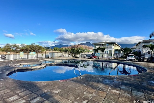 view of swimming pool with a mountain view, a community hot tub, and a patio