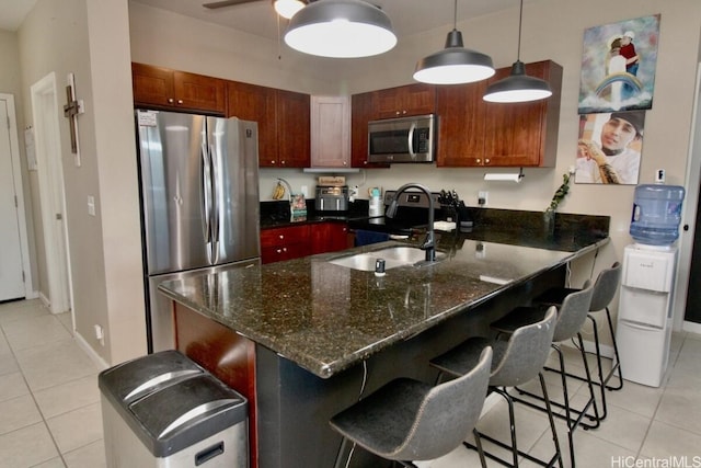 kitchen with dark stone counters, a kitchen breakfast bar, sink, appliances with stainless steel finishes, and kitchen peninsula