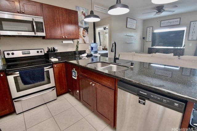 kitchen with pendant lighting, dark stone counters, sink, light tile patterned floors, and appliances with stainless steel finishes