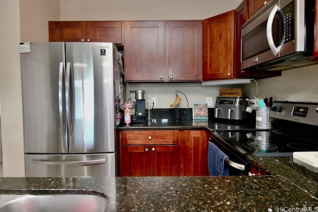 kitchen with appliances with stainless steel finishes and dark stone countertops