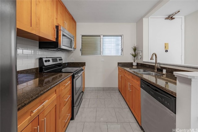 kitchen with dark stone counters, sink, tasteful backsplash, light tile patterned flooring, and stainless steel appliances