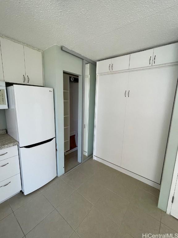 unfurnished bedroom featuring white refrigerator, a textured ceiling, and a closet