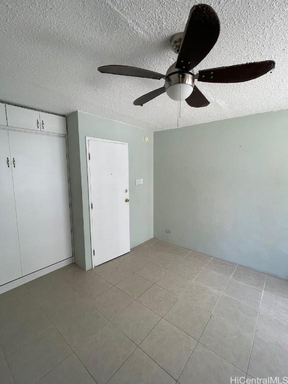 unfurnished bedroom with a textured ceiling, a closet, and ceiling fan