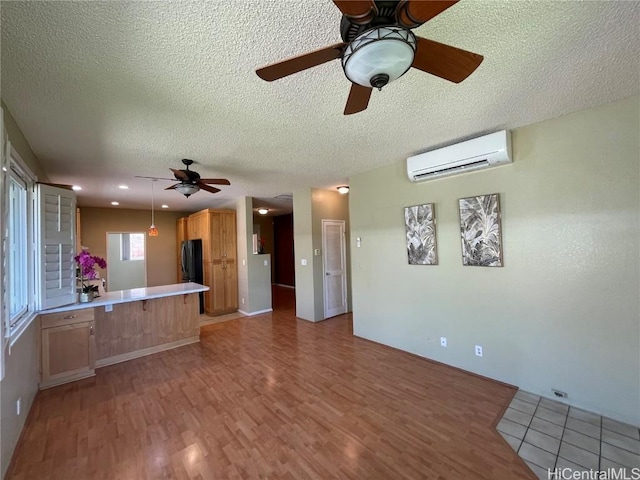 kitchen featuring a wall mounted air conditioner, kitchen peninsula, a textured ceiling, and stainless steel refrigerator