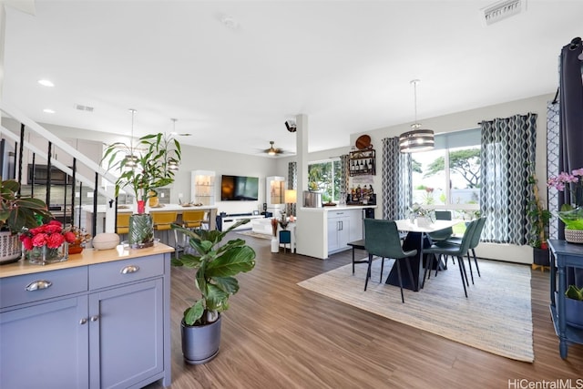 kitchen featuring pendant lighting, ceiling fan with notable chandelier, and dark wood-type flooring