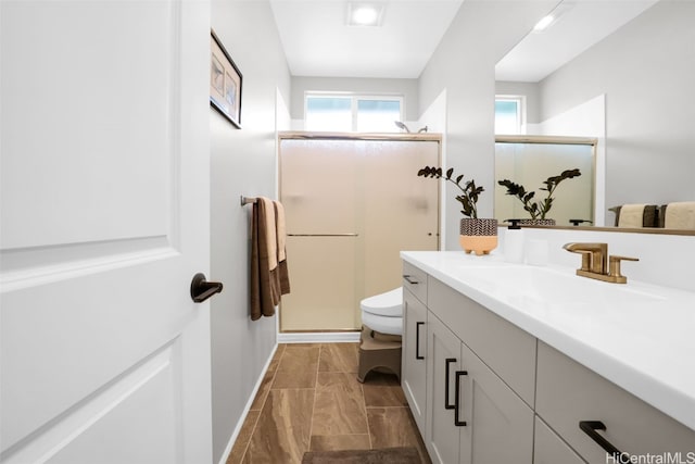 bathroom featuring a shower with door, vanity, and toilet