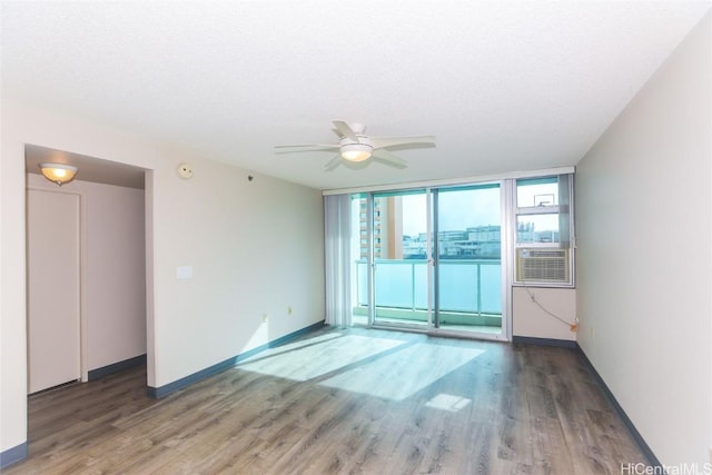 spare room with hardwood / wood-style floors, cooling unit, ceiling fan, a textured ceiling, and a wall of windows