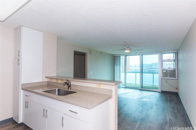 kitchen with white cabinets, expansive windows, sink, a textured ceiling, and kitchen peninsula