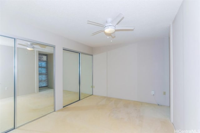 unfurnished bedroom featuring carpet flooring, ceiling fan, a textured ceiling, and multiple closets