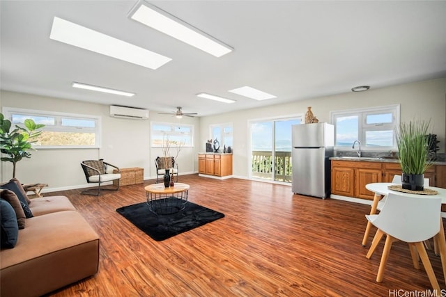 living room featuring a wall mounted air conditioner, ceiling fan, wood-type flooring, and sink