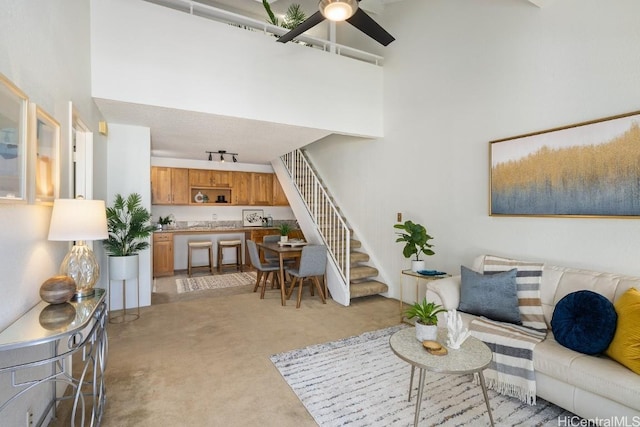 carpeted living room featuring ceiling fan and a towering ceiling