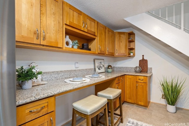 kitchen with light stone countertops, a breakfast bar, and a textured ceiling