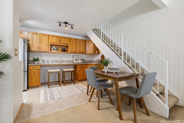 kitchen with stainless steel fridge, light colored carpet, and a textured ceiling