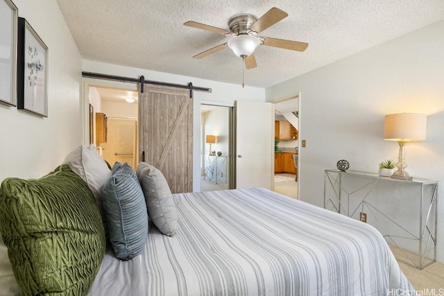 bedroom featuring ensuite bath, ceiling fan, a textured ceiling, and a barn door