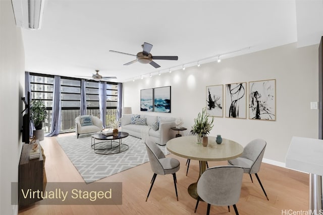 dining room featuring ceiling fan, rail lighting, light hardwood / wood-style floors, and a wall of windows