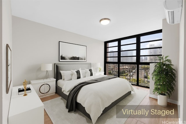 bedroom with light hardwood / wood-style flooring and a wall of windows