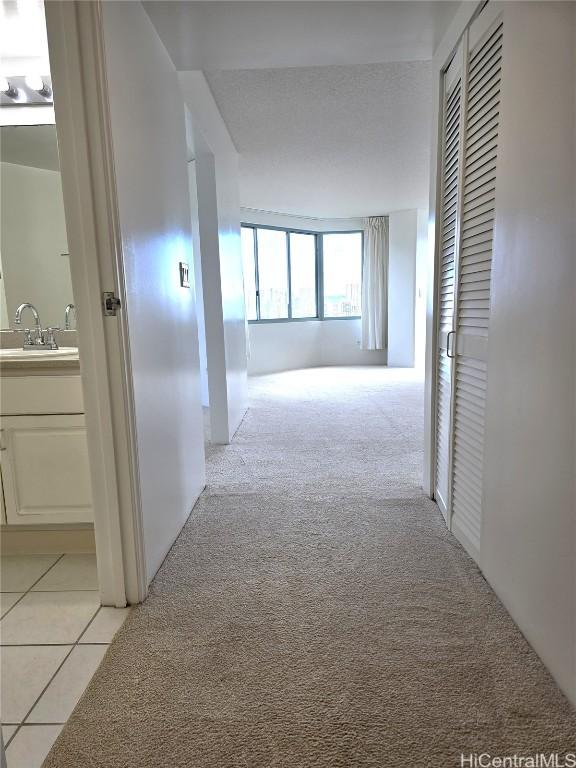 hallway with light colored carpet and sink