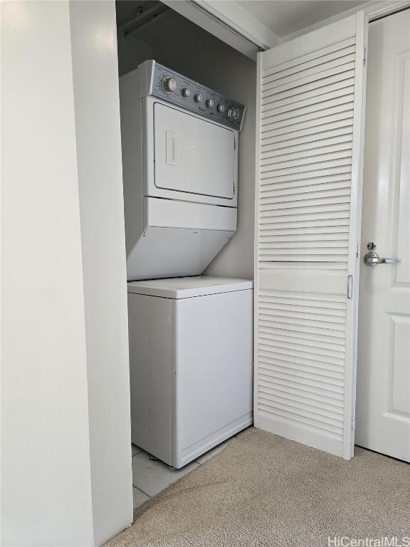 clothes washing area with light colored carpet and stacked washer and dryer