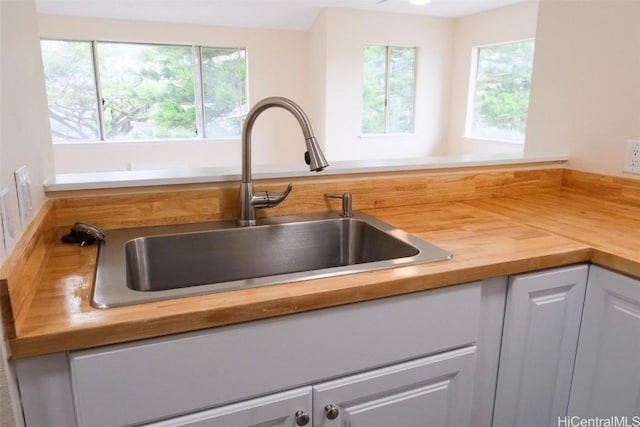 room details featuring wooden counters, white cabinets, and sink