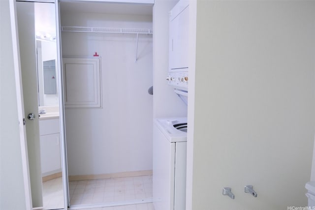 laundry area featuring laundry area, stacked washer / drying machine, baseboards, and tile patterned floors