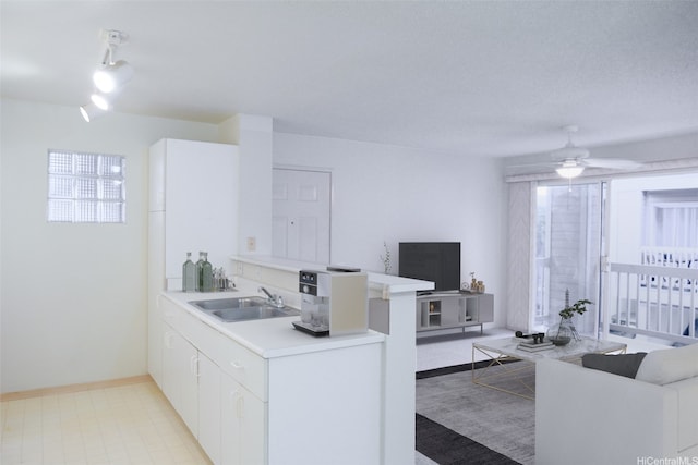 kitchen featuring a sink, light countertops, a ceiling fan, baseboards, and white cabinetry