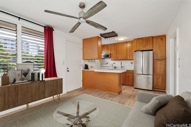 kitchen featuring kitchen peninsula, appliances with stainless steel finishes, a textured ceiling, and light hardwood / wood-style flooring