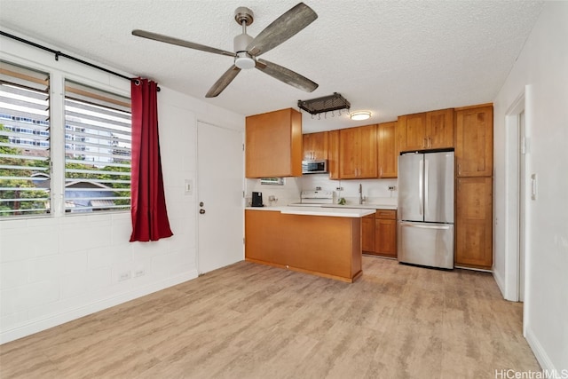 kitchen with light hardwood / wood-style flooring, ceiling fan, a textured ceiling, kitchen peninsula, and stainless steel appliances