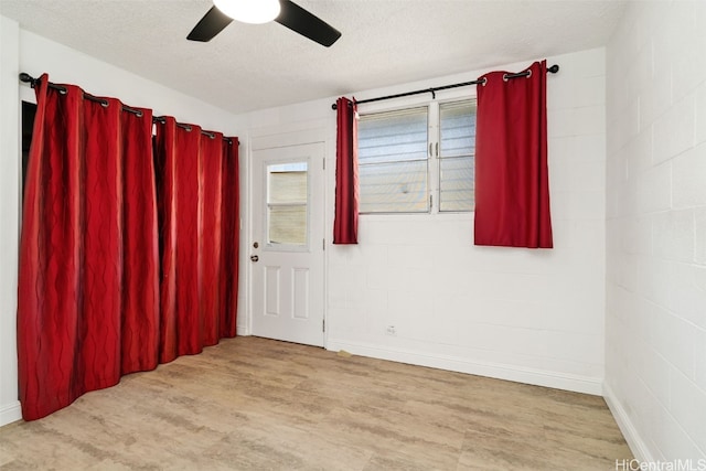 spare room with a textured ceiling, light wood-type flooring, and ceiling fan