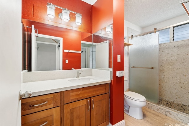 bathroom with an enclosed shower, vanity, toilet, and a textured ceiling