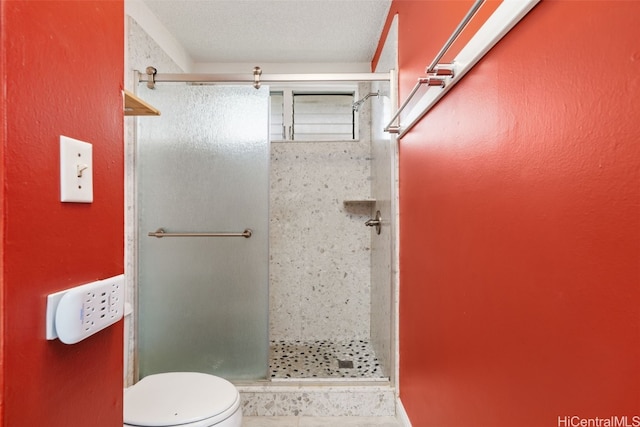 bathroom featuring a textured ceiling, toilet, and a shower with shower door