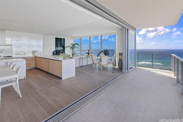 kitchen with light brown cabinetry, a water view, white cabinetry, and a wealth of natural light