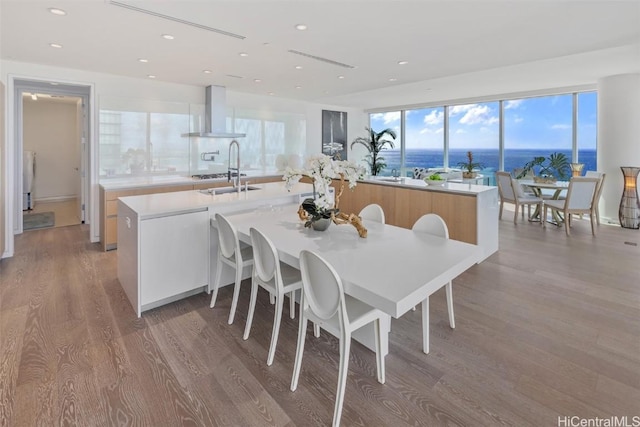 dining space with light wood-type flooring, a water view, and sink