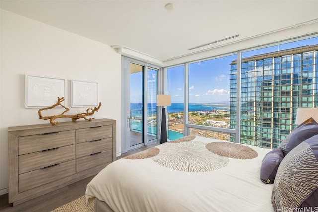 bedroom with hardwood / wood-style flooring, access to outside, and multiple windows