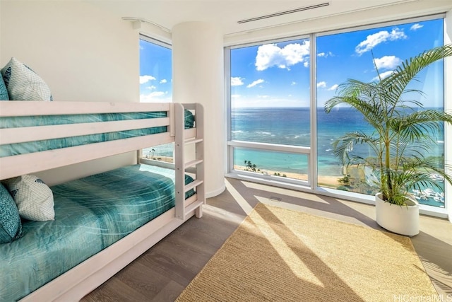 bedroom featuring a water view, multiple windows, and hardwood / wood-style flooring