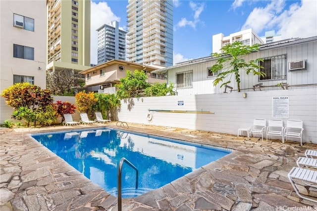 view of pool featuring a wall mounted air conditioner and a patio area