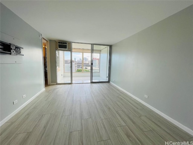 unfurnished room featuring light wood-type flooring, floor to ceiling windows, and a wall mounted AC