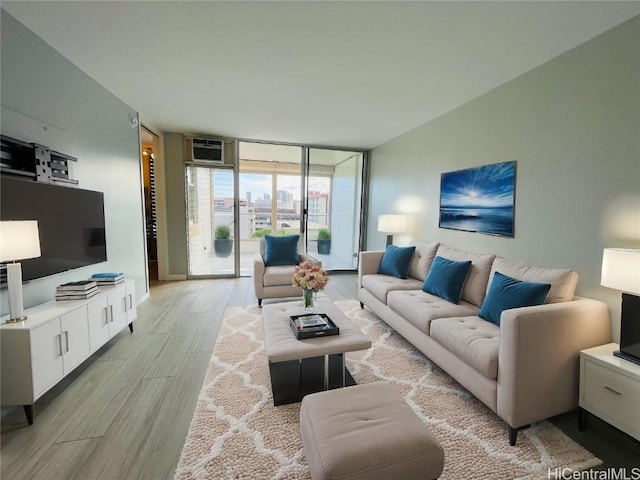 living room featuring light wood-type flooring, a wall mounted air conditioner, and expansive windows