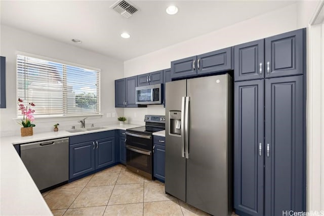 kitchen featuring blue cabinetry, sink, light tile patterned floors, and stainless steel appliances