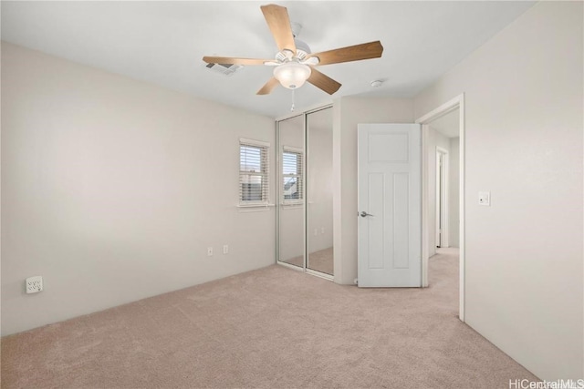 unfurnished bedroom with ceiling fan, light carpet, and a closet